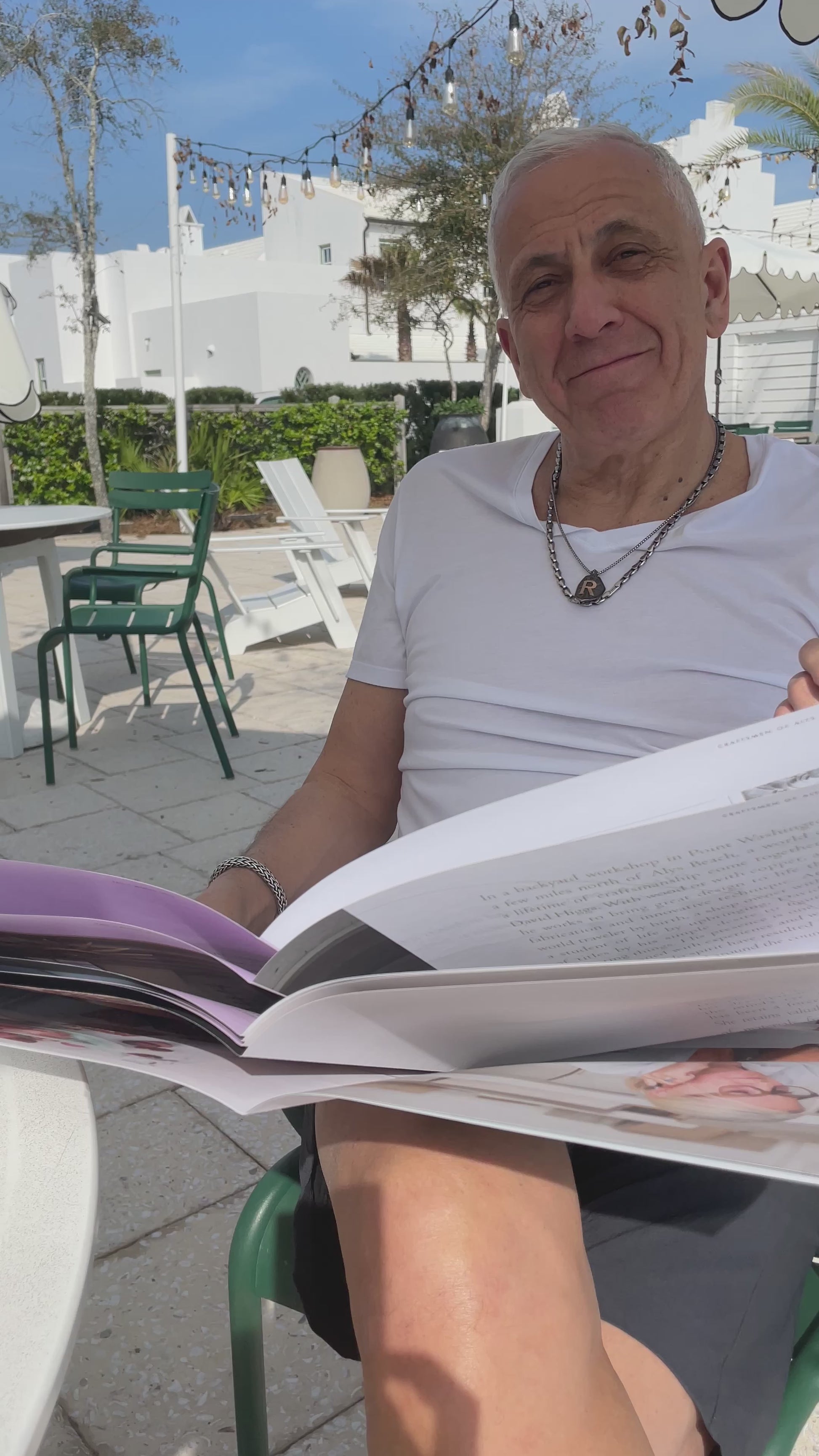 Man putting on his round tortoise and blue designer reading glasses, the "London" style, while reading a news paper