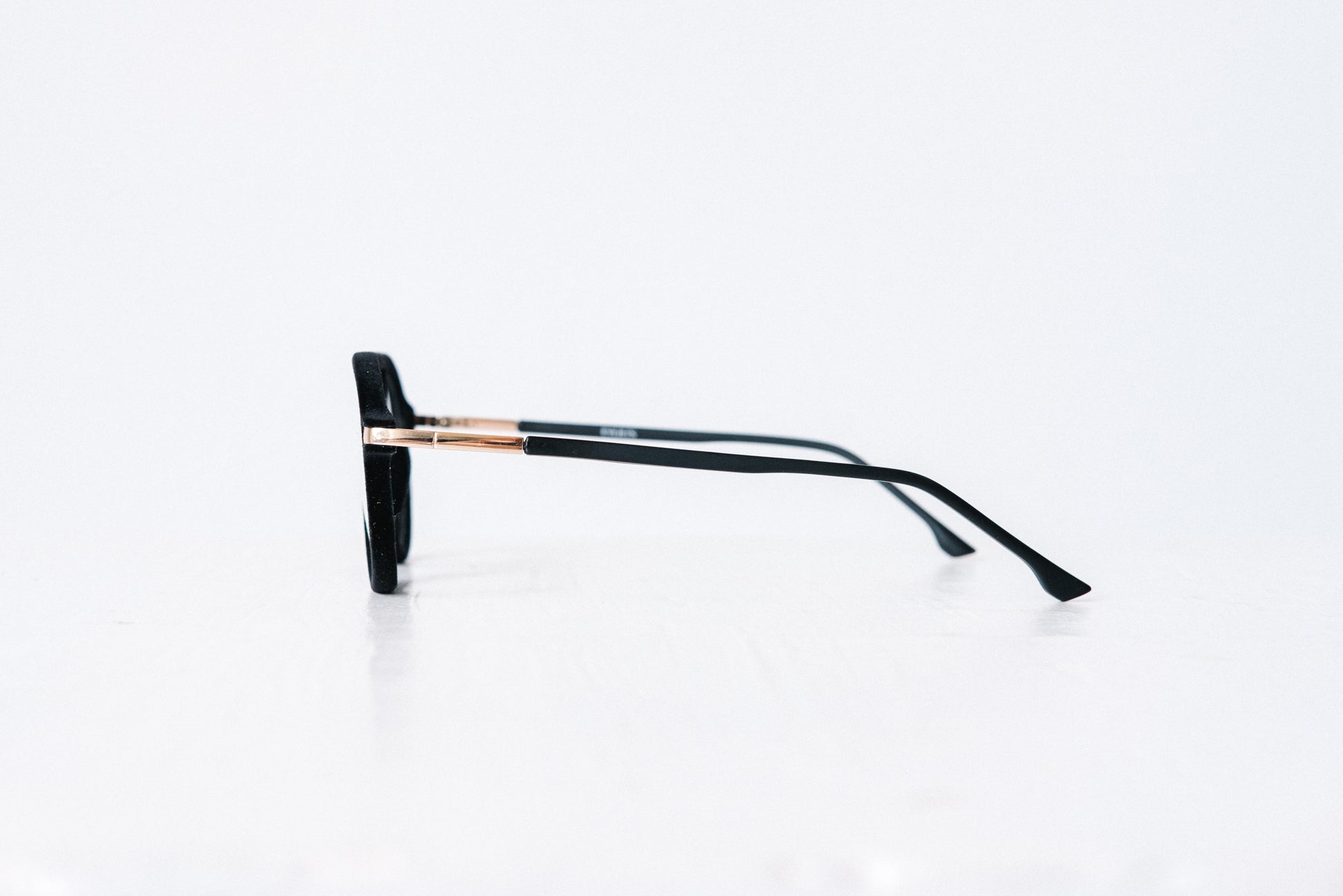 Side view of black velvet aviator glasses with matte black temples, displayed on a white background. The soft velvet texture gives a luxurious finish, available as reading glasses or blue light blocking glasses.