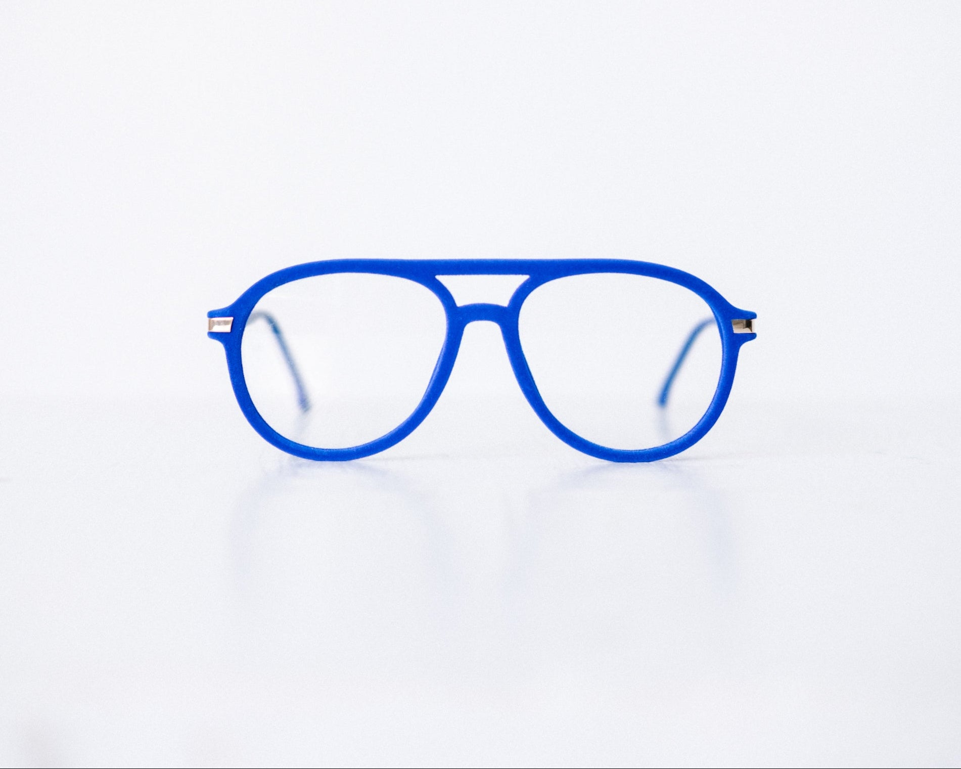 Front view of blue velvet aviator glasses with matte blue temples, displayed on a white background. These frames feature a soft velvet finish and are available as reading glasses or blue light blocking glasses.