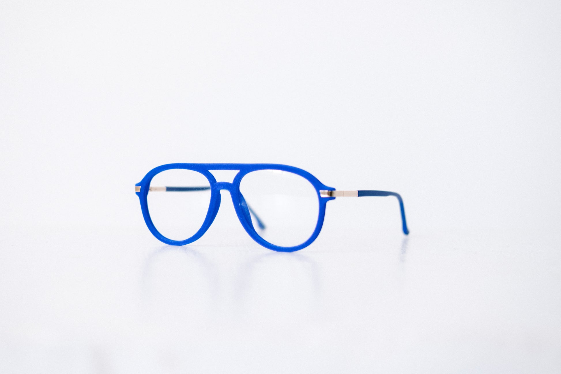 Side view of blue velvet aviator glasses with matte blue temples, displayed on a white background. These frames feature a soft velvet finish and are available as reading glasses or blue light blocking glasses.