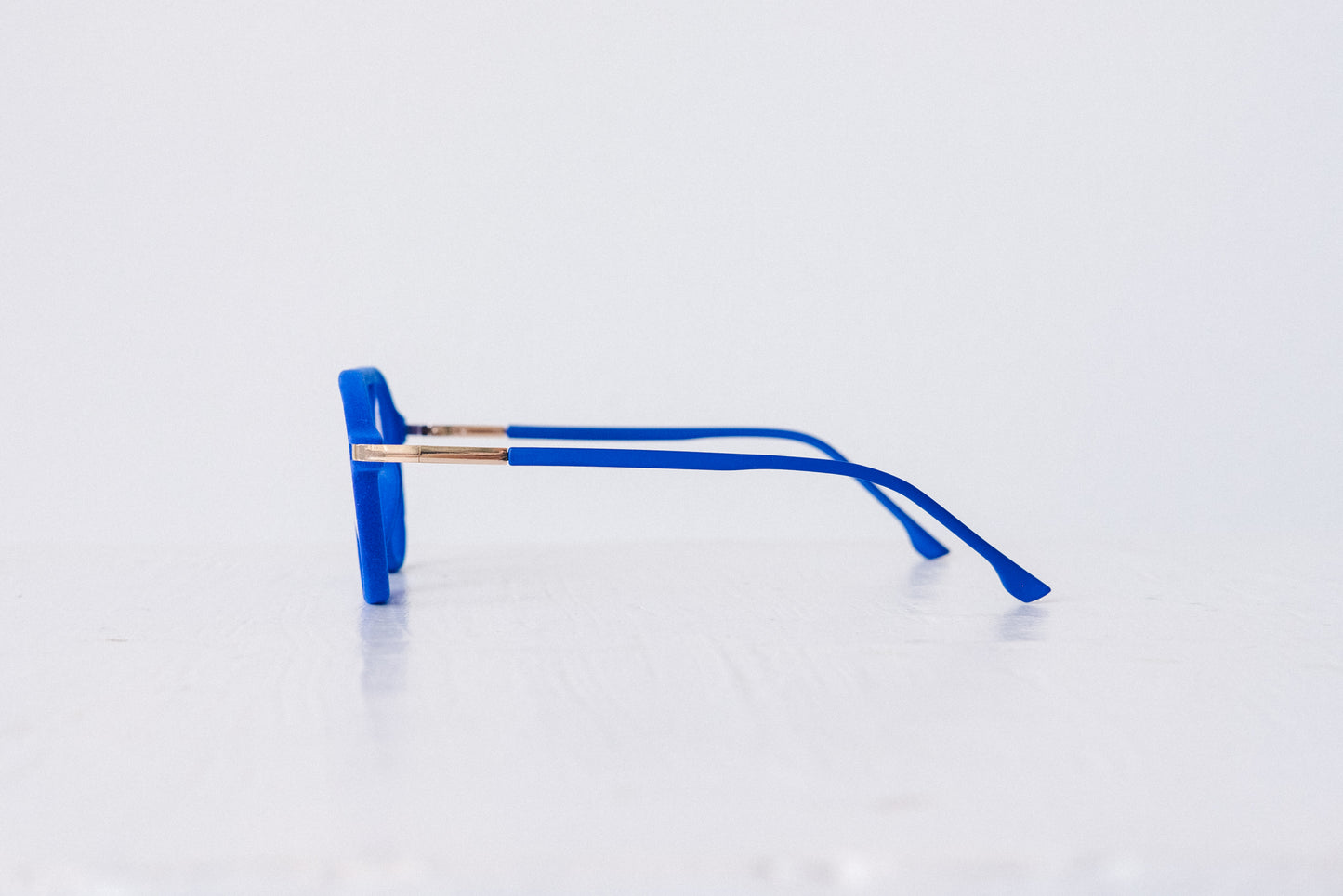 Side view of blue velvet aviator glasses with matte blue temples, displayed on a white background. These frames feature a soft velvet finish and are available as reading glasses or blue light blocking glasses.