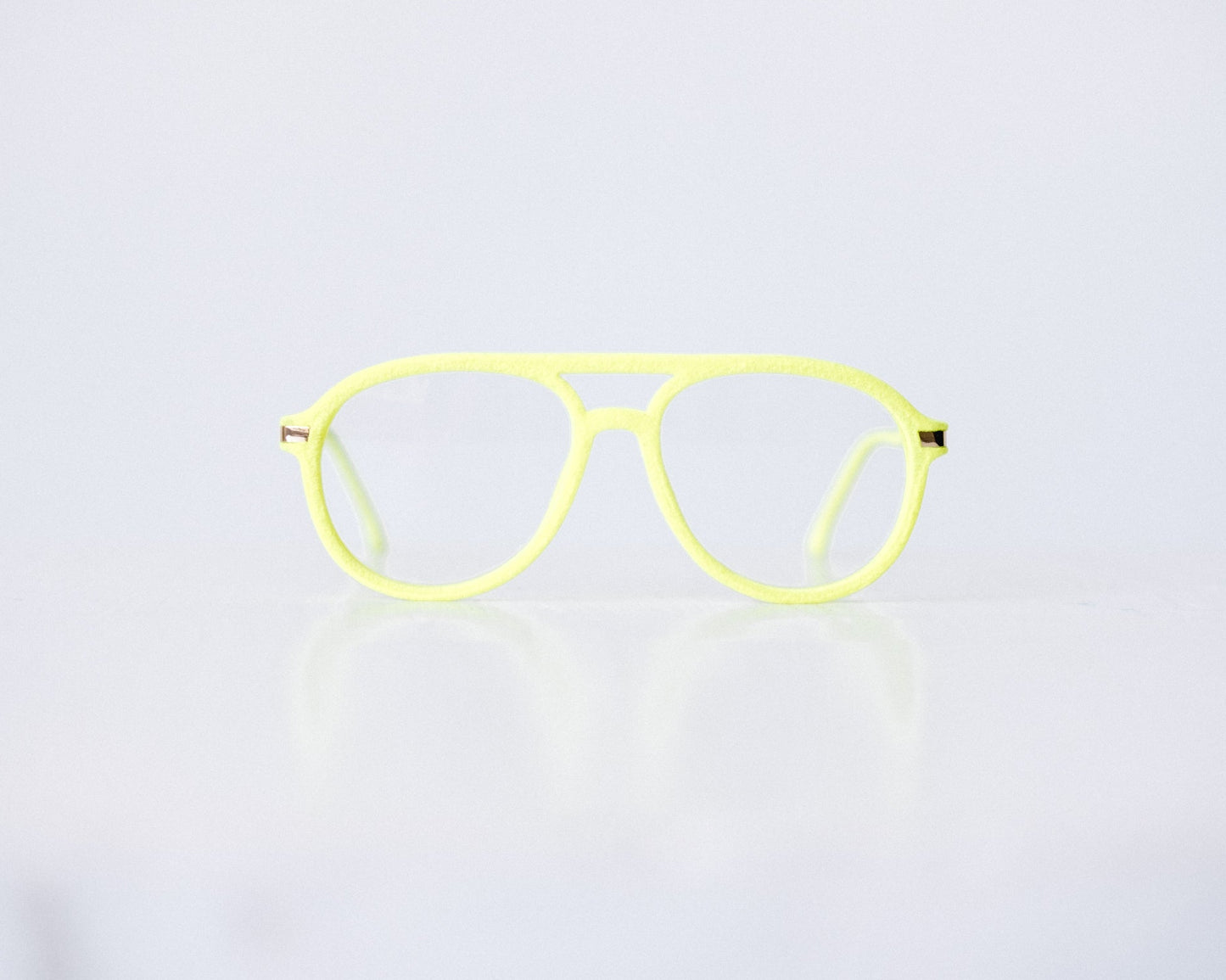 Front view of neon green and neon yellow velvet aviator glasses with matte temples, displayed on a white background. The bold, vibrant frame features a soft velvet texture and is available as reading glasses or blue light blocking glasses.