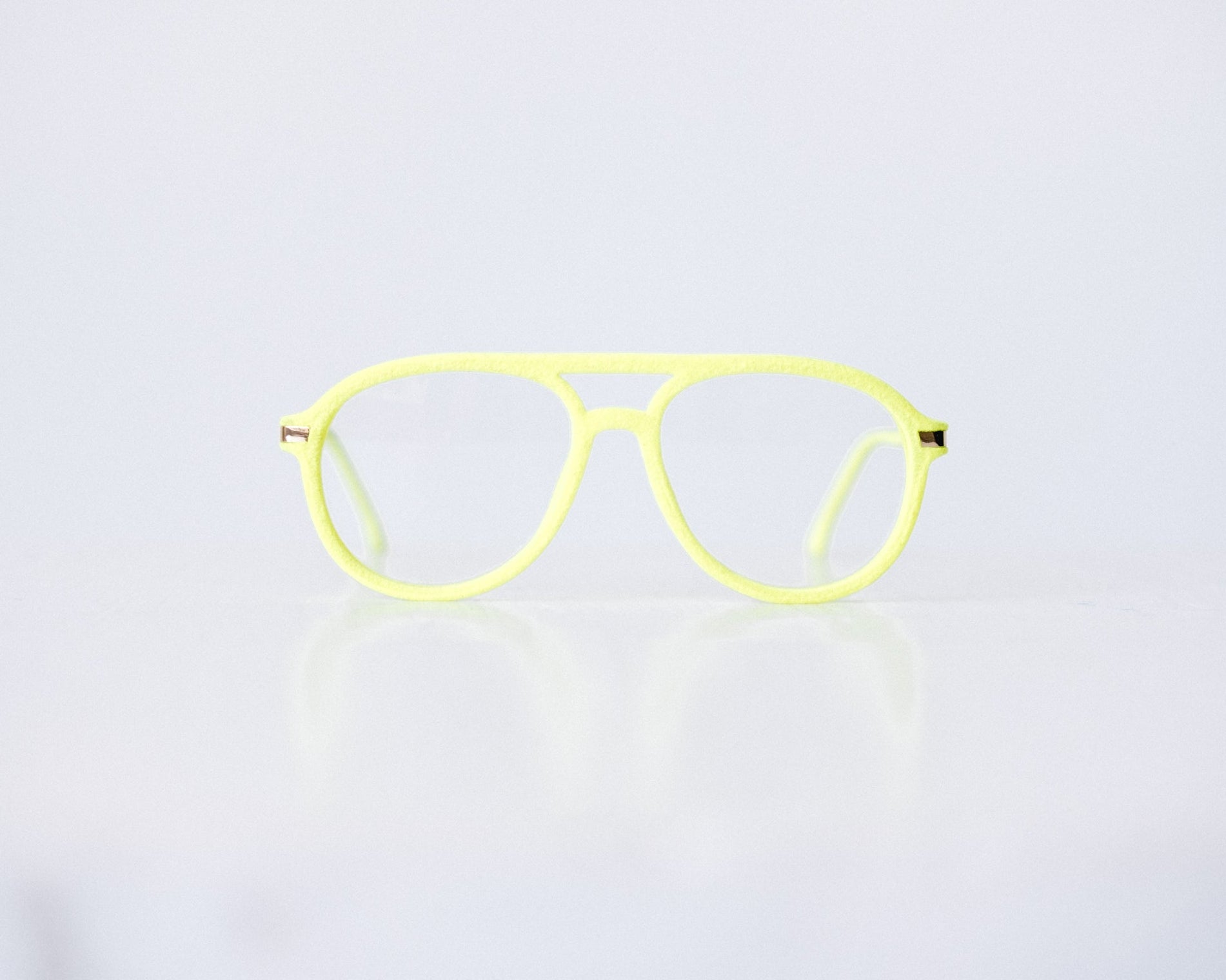 Front view of neon green and neon yellow velvet aviator glasses with matte temples, displayed on a white background. The bold, vibrant frame features a soft velvet texture and is available as reading glasses or blue light blocking glasses.