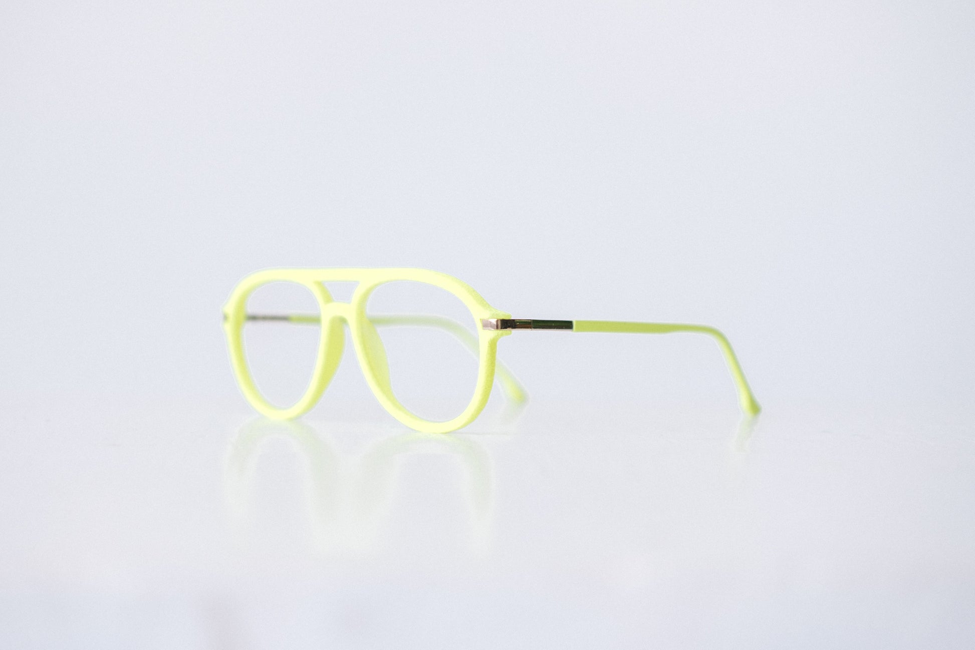 Side view of neon green and neon yellow velvet aviator glasses with matte temples, displayed on a white background. The bold, vibrant frame features a soft velvet texture and is available as reading glasses or blue light blocking glasses.