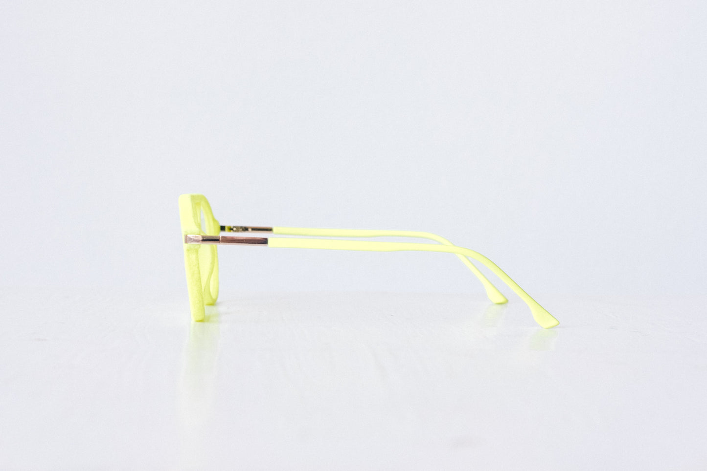 Side view of neon green and neon yellow velvet aviator glasses with matte temples, displayed on a white background. The bold, vibrant frame features a soft velvet texture and is available as reading glasses or blue light blocking glasses.
