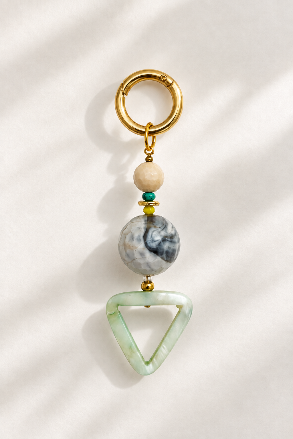 Natural gemstone handmade bag charm keychain that double as a eyeglasses holder with gold hardware, an assortment of stone and a green triangle