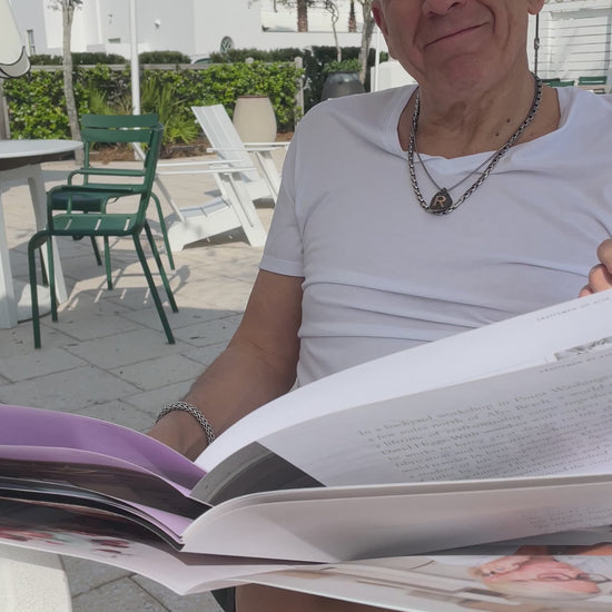 Man putting on his round tortoise and blue designer reading glasses, the "London" style, while reading a news paper